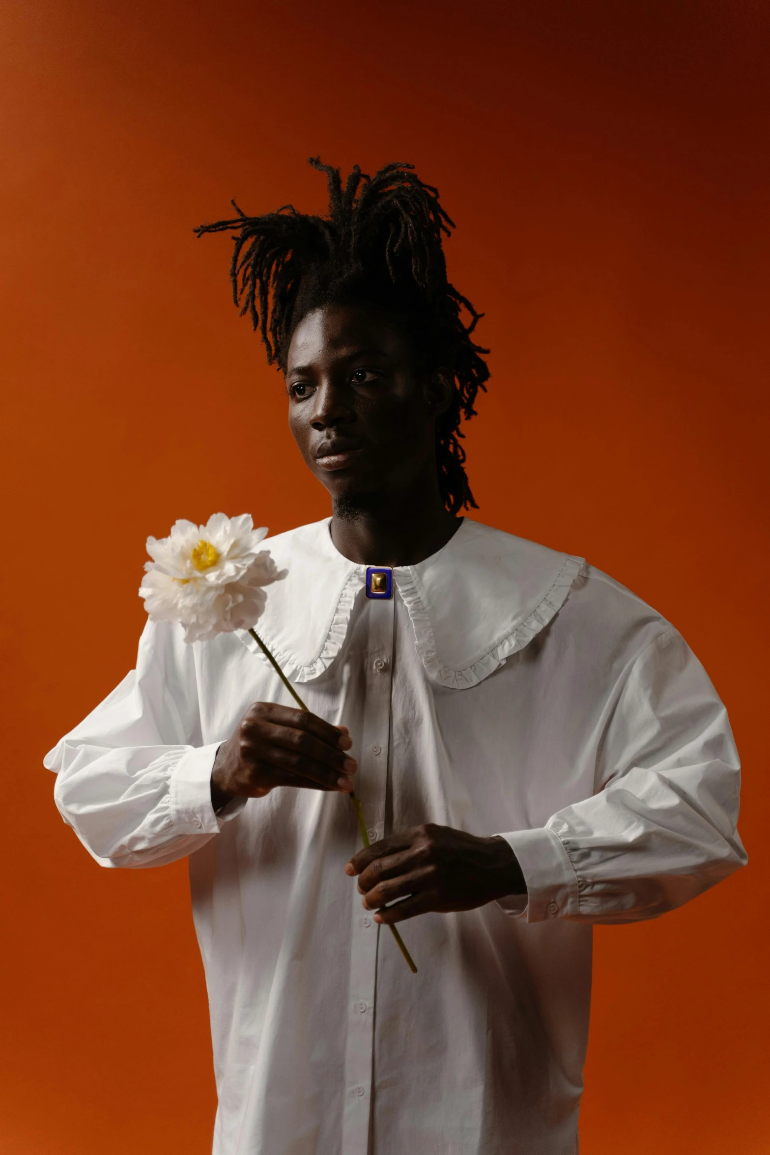 a man in a white shirt holding a flower, an album cover, inspired by Charles Martin, afrofuturism, adut akech, loosely cropped, holding daisy, official photo