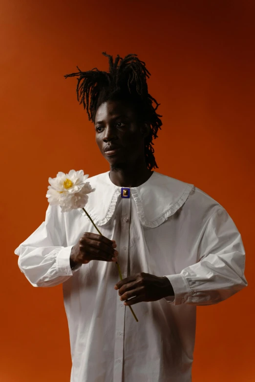 a man in a white shirt holding a flower, an album cover, inspired by Charles Martin, afrofuturism, adut akech, loosely cropped, holding daisy, official photo