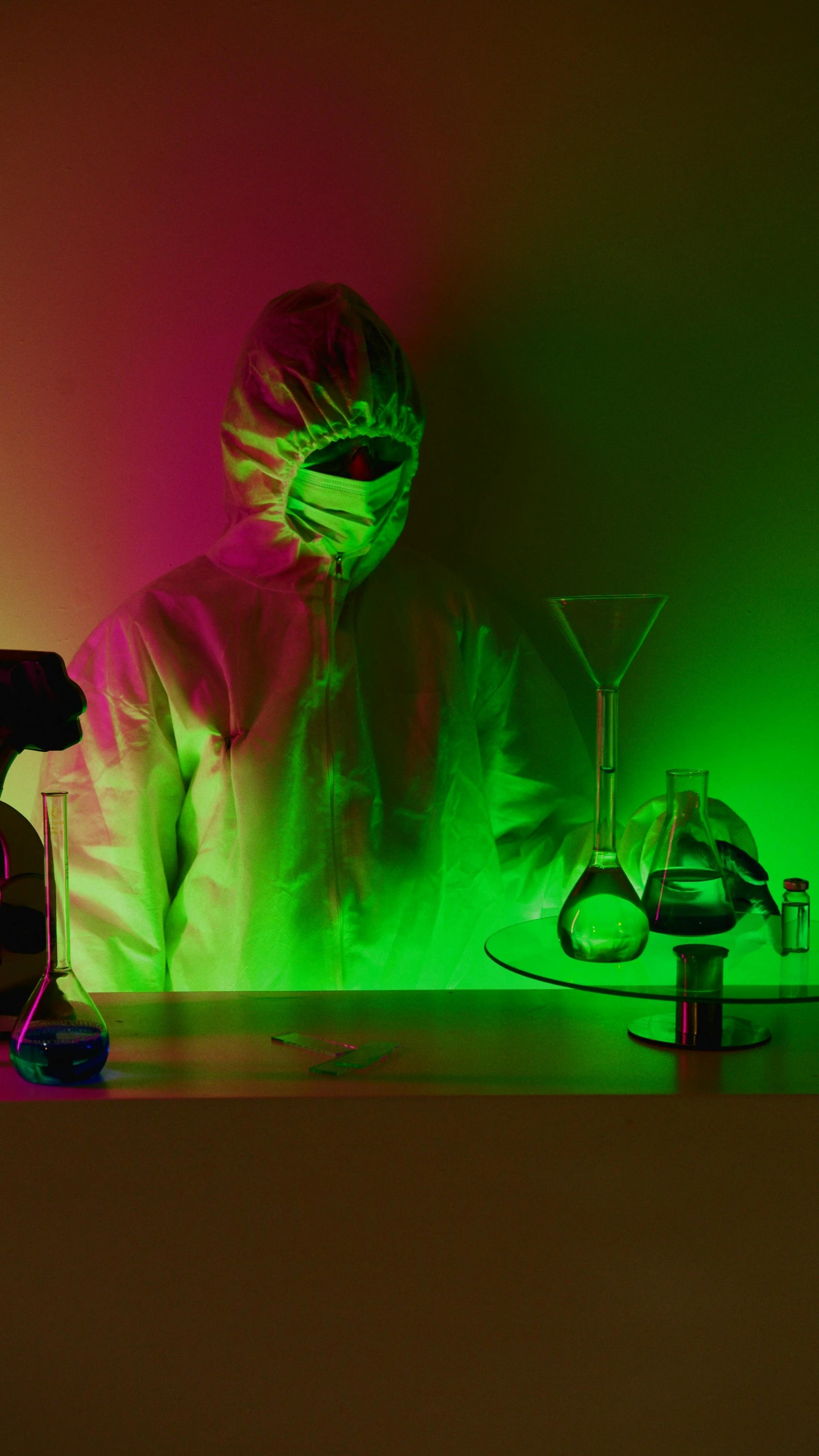 a person sitting at a table in front of a green light, by Mark Arian, pexels, holography, with a lab coat, sterile colours, biopunk suit, photo illustration