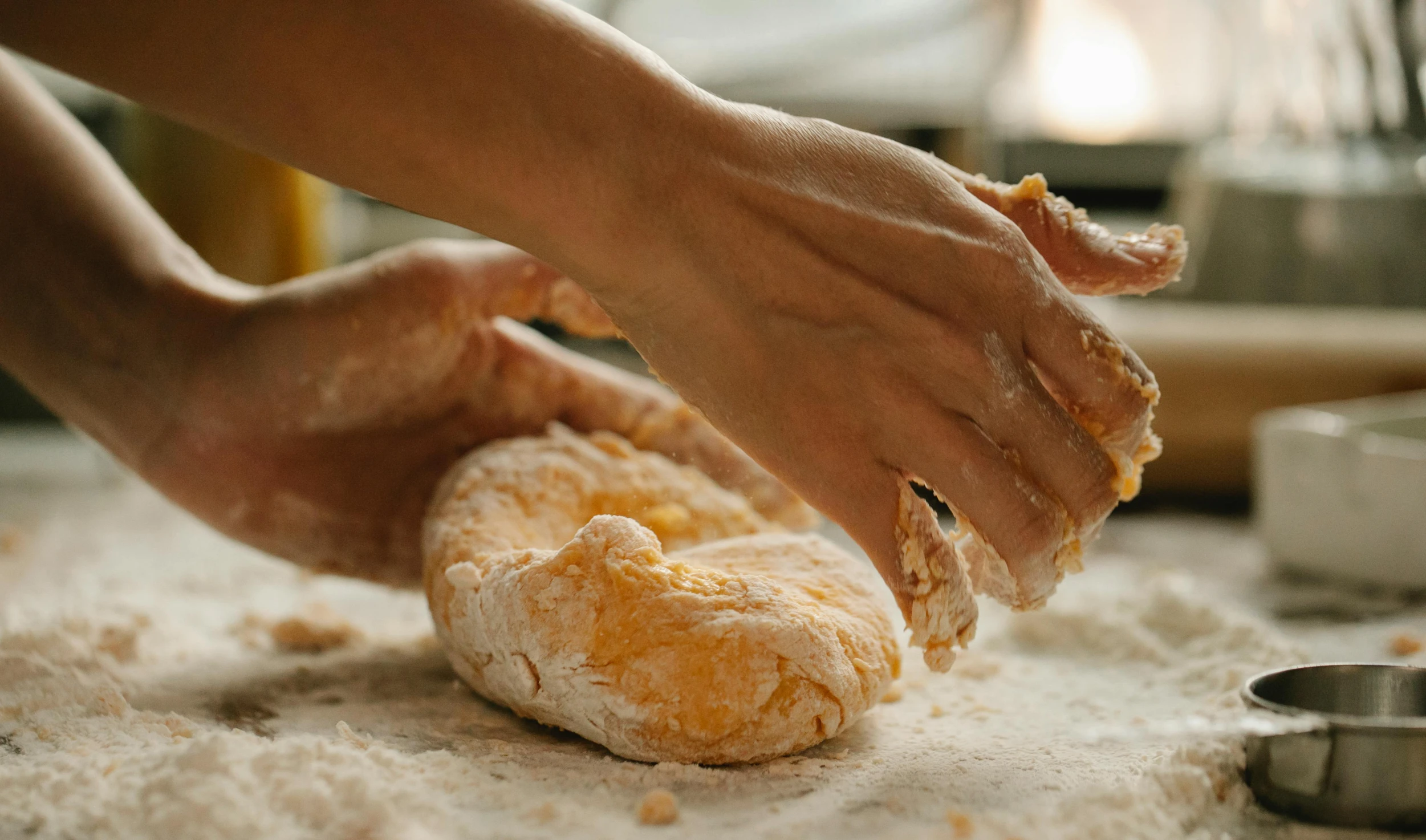 a close up of a person kning doughnuts on a table, a marble sculpture, by Liza Donnelly, trending on pexels, calzone zone, golden glow, covered in salt, paw pads