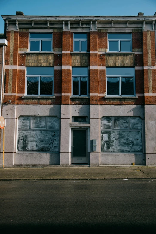 a tall brick building sitting on the side of a road, unsplash, graffiti, shop front, unfinished, thumbnail, wide film still