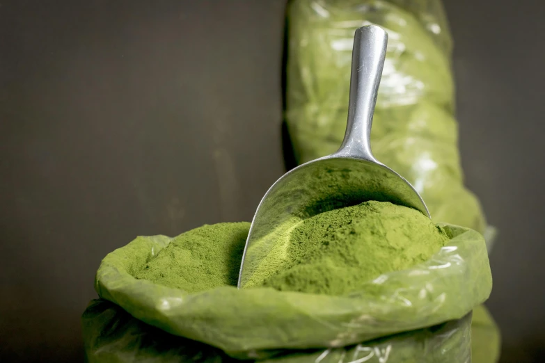 a scoop of matcha sitting on top of a pile of lettuce, by Julia Pishtar, trending on unsplash, magic powder, marvelous designer substance, full face, metalic green