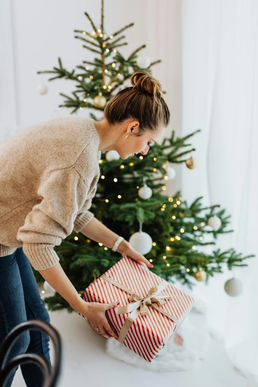 a woman opening a christmas present in front of a christmas tree, by Alice Mason, happening, profile image, casually dressed, trend, helpful