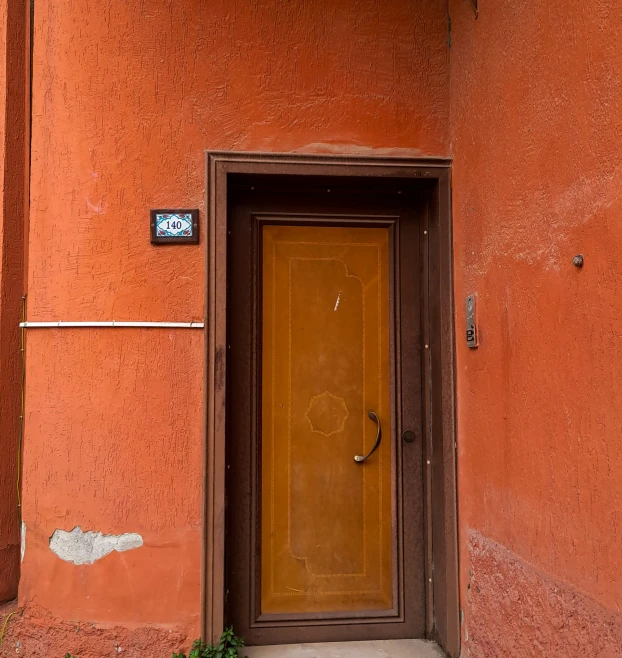 a brown door sitting on the side of a building, by Sven Erixson, pexels contest winner, orange color scheme, alexander abdulov, dull red, today\'s featured photograph 4k