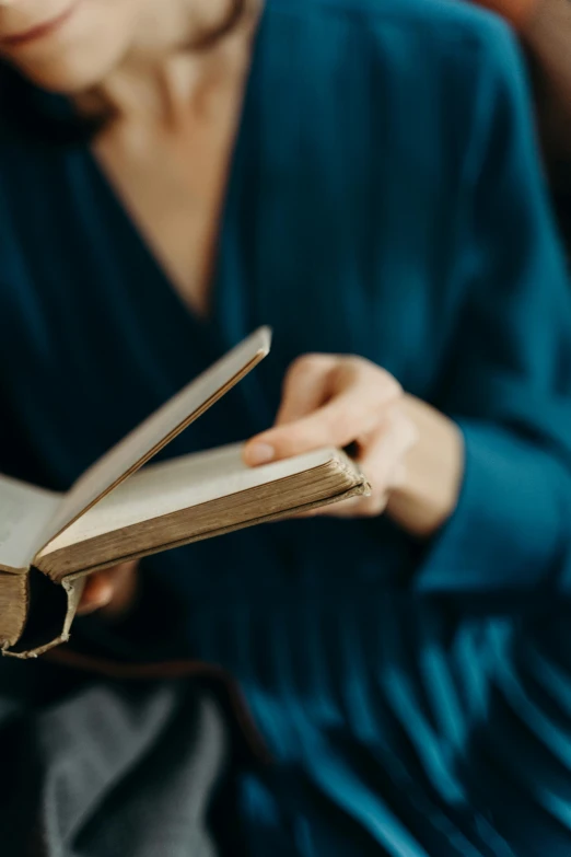 a woman sitting on a couch reading a book, by Carey Morris, trending on unsplash, renaissance, wearing blue robe, dynamic closeup, inspect in inventory image, religious