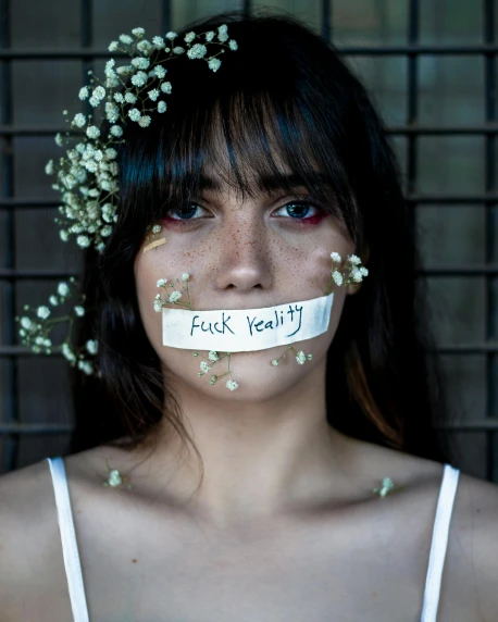a woman with a piece of paper taped over her mouth, inspired by Elsa Bleda, trending on pexels, feminist art, white flower crown, lgbt, charli xcx, filthy