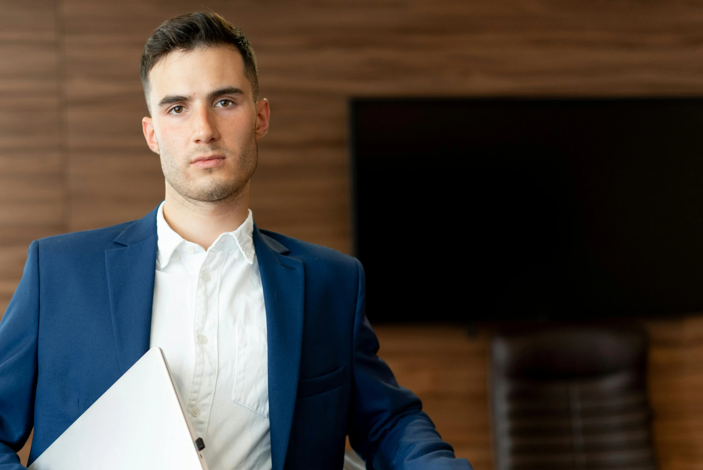 a man in a blue suit holding a piece of paper, pexels contest winner, hurufiyya, f 1 driver charles leclerc, office clothes, serious look, 21 years old