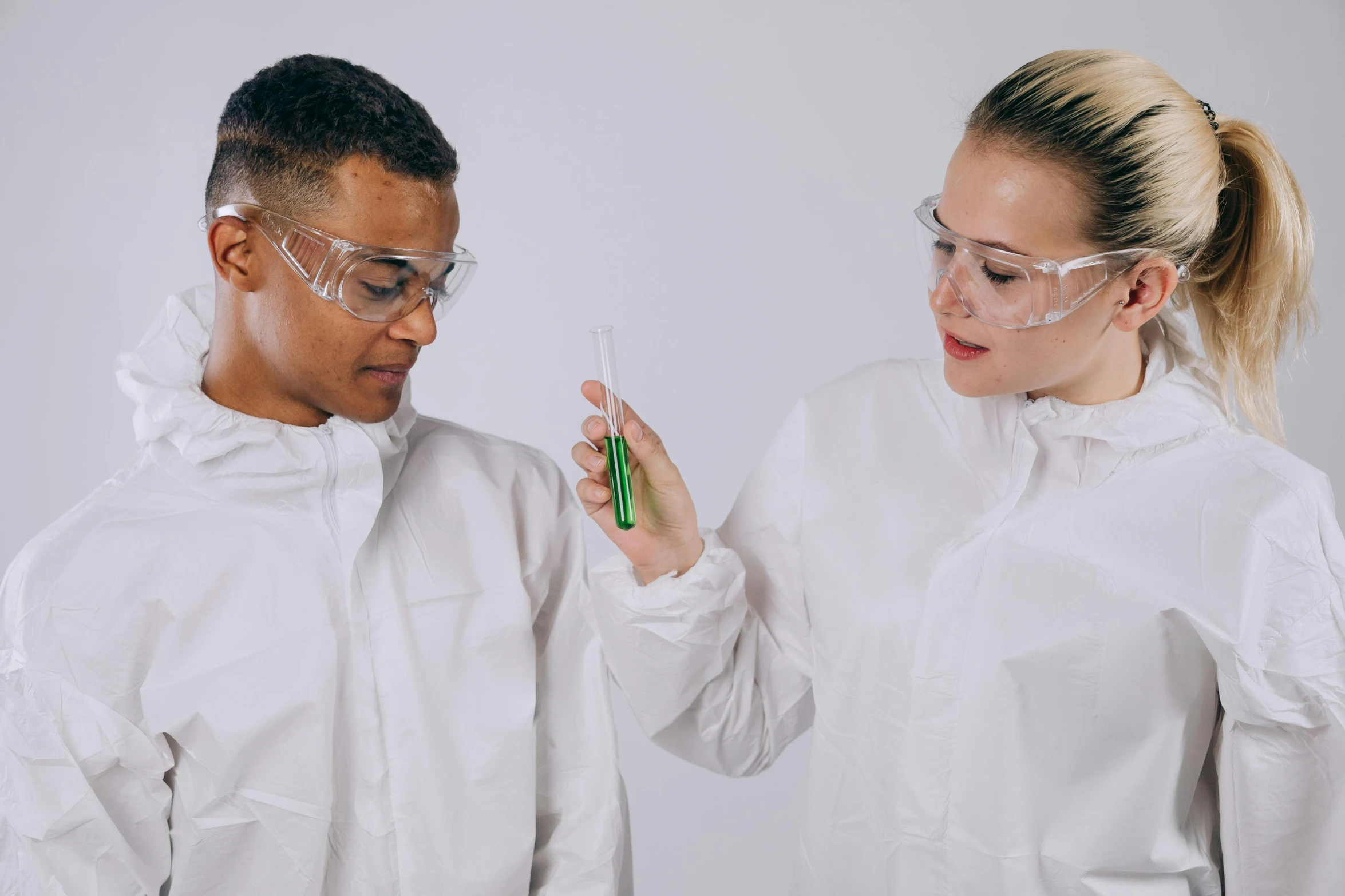 a couple of people standing next to each other, trending on pexels, science lab, pouring techniques, academic clothing, with a white complexion