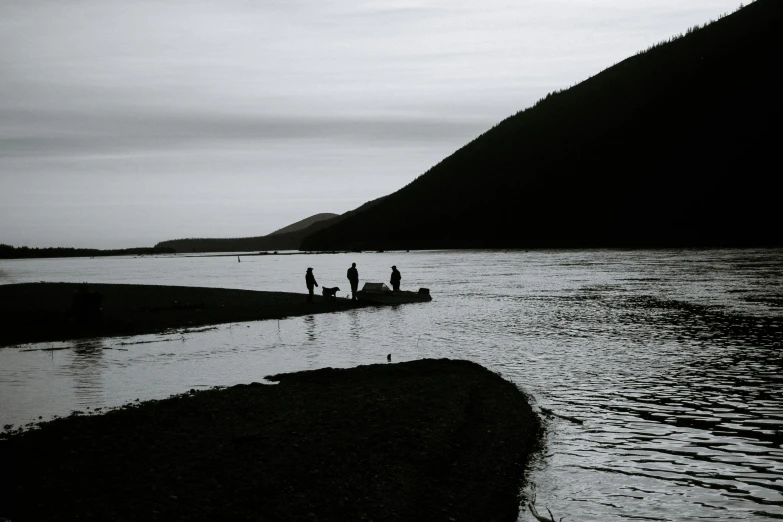 a group of people standing next to a body of water, a black and white photo, by Thomas Furlong, pexels contest winner, hurufiyya, an island made of caviar, dark dingy, fishing, late summer evening