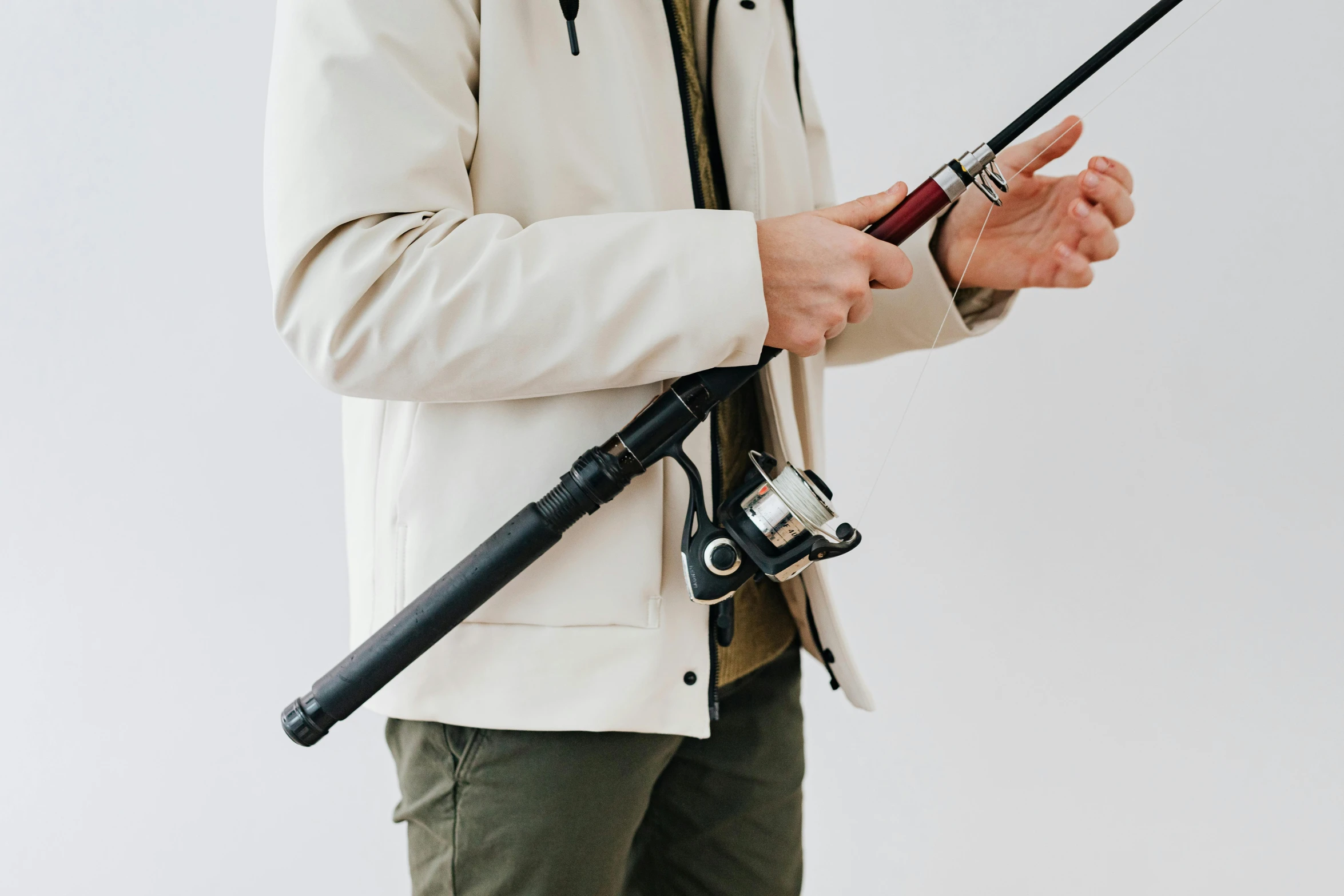 a man in a white jacket holding a fishing rod, by Carey Morris, trending on pexels, hurufiyya, holding a blaster, detailed product image, lachlan bailey, detailed high resolution