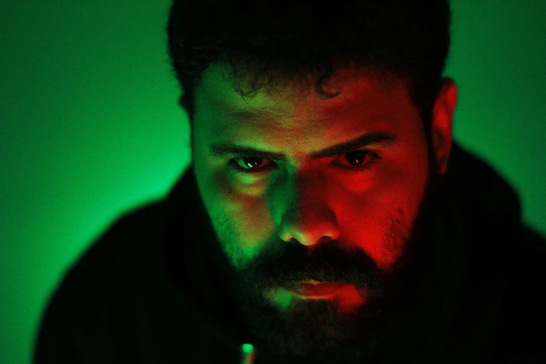 a man with a beard stares at the camera, an album cover, inspired by Elsa Bleda, pexels contest winner, serial art, red and green lighting, sayem reza, still frame from a movie, nightvision