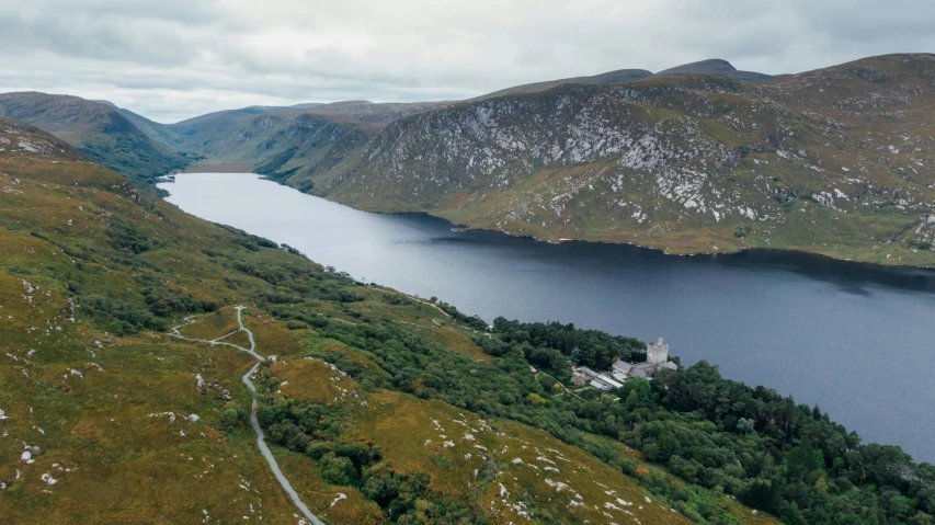 a large body of water sitting on top of a lush green hillside, by Eamon Everall, castle on the mountain, arial shot, a lake between mountains, thumbnail