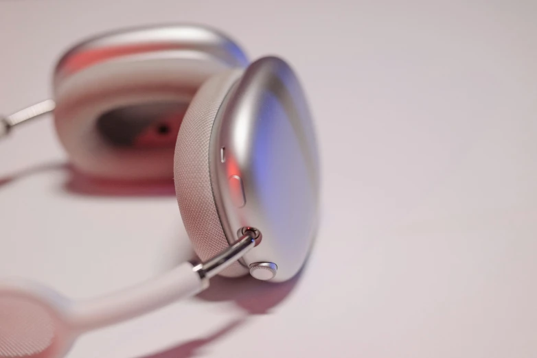 a pair of headphones sitting on top of a table, silver dechroic details, swoosh, right side profile, apple