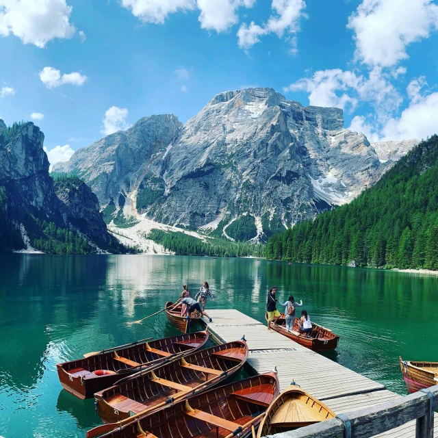 a group of boats sitting on top of a lake, pexels contest winner, dolomites in background, fan favorite, wooden boat, green waters