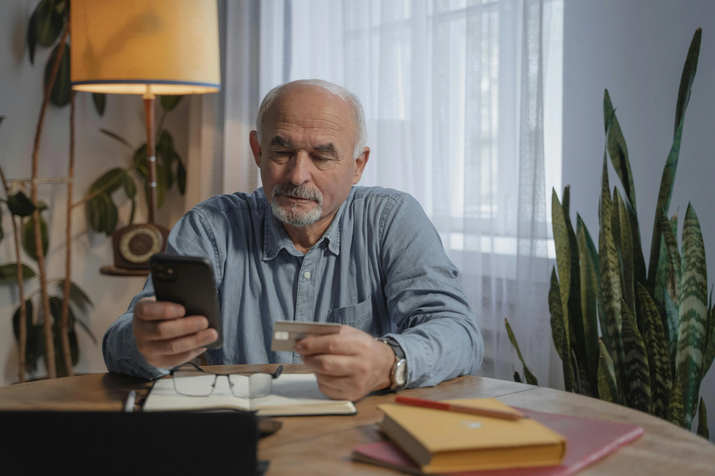 a man sitting at a table looking at his cell phone, an elderly, avatar image, professional shot, thumbnail