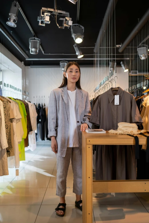 a woman standing in front of a rack of clothes, trending on unsplash, gutai group, sangsoo jeong, wearing a linen shirt, presenting wares, thumbnail