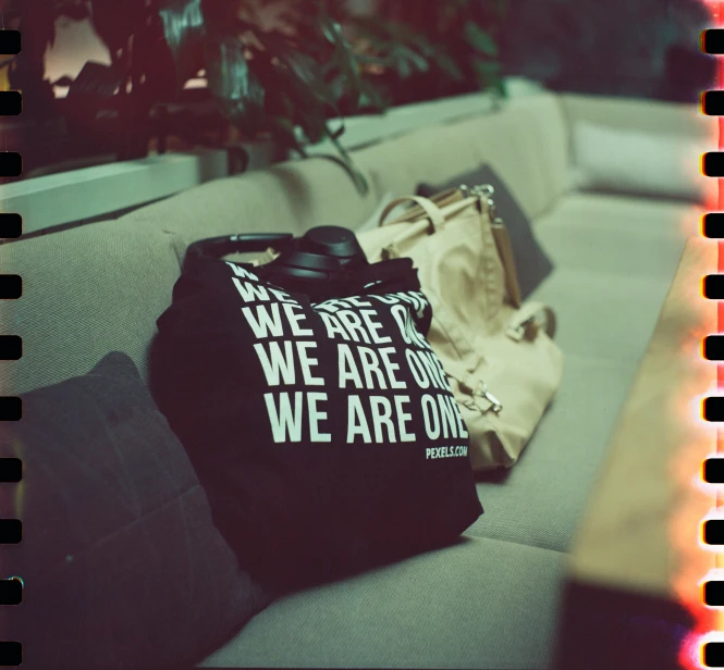 a couple of bags sitting on top of a couch, by Caro Niederer, unsplash, graffiti, black t shirt, we go, on a coffee table, in a black hoodie