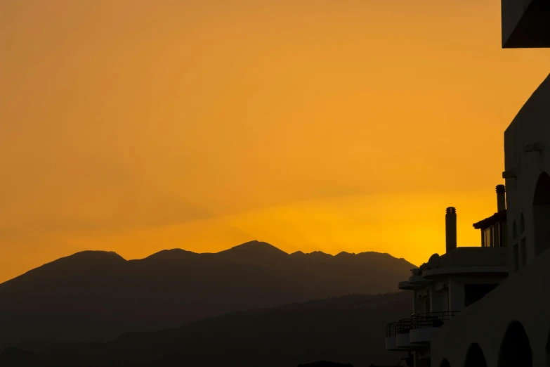 the sun is setting over the mountains in the distance, by Alexis Grimou, pexels contest winner, golden cityscape, simplistic, ocher, marbella landscape