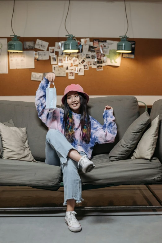 a woman sitting on a couch in a room, inspired by Kim Jeong-hui, pexels contest winner, she is wearing streetwear, joy ang, faded hat, colored milk tea