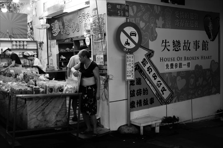 a couple of people standing in front of a food stand, a black and white photo, by Gang Hui-an, pexels, graffiti, moonless night, street signs, 中 元 节, july 2 0 1 1