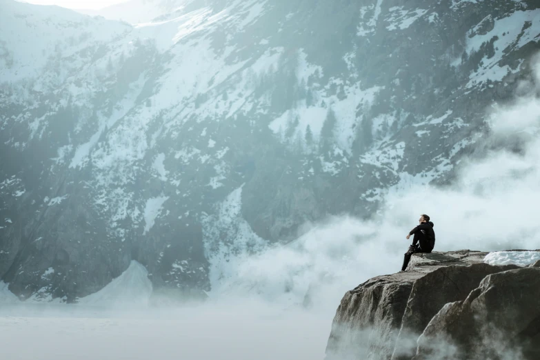 a person sitting on a rock in front of a mountain, inspired by Michael Komarck, pexels contest winner, cold mist, extreme cold, avatar image, extremely high resolution