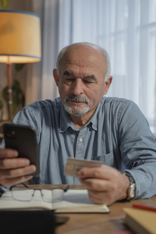 a man sitting at a table with a credit card in his hand, grandfatherly, checking her phone, uploaded, maintenance