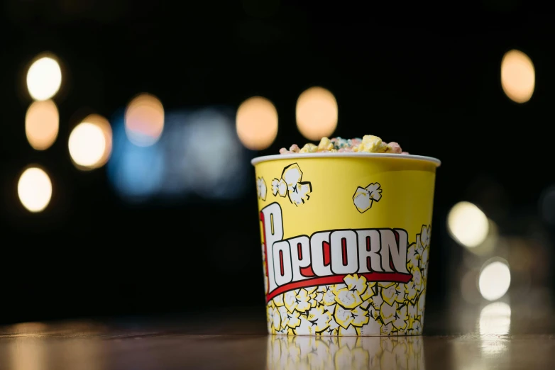 a popcorn cup sitting on top of a table, arthouse cinema, yellow, thumbnail, exterior shot