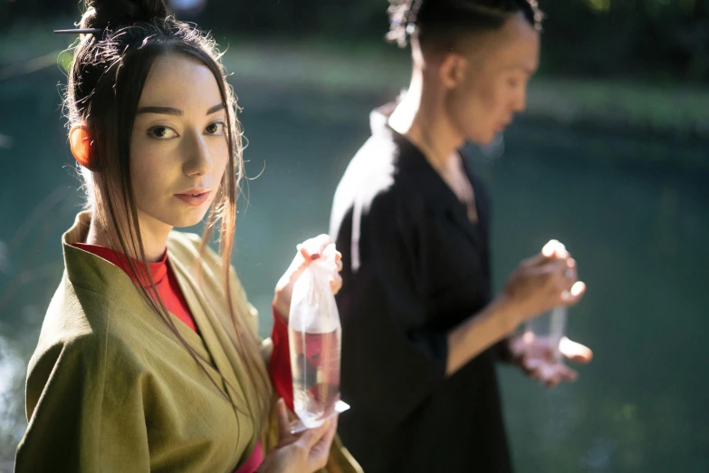 a woman in a kimono standing next to a man, inspired by Fu Baoshi, pexels contest winner, holding a bottle, sydney park, ( ( theatrical ) ), closeup fantasy with water magic