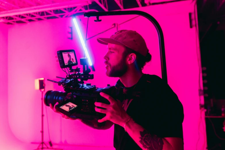 a man holding a camera in front of a pink light, red lightsaber, production ig, avatar image, crane shot