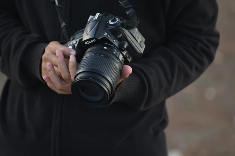 a man holding a camera in his hands, by David Simpson, unsplash, photorealism, shot on nikon z9, fall season, nikkon, 4 0 0 mm f 1. 2