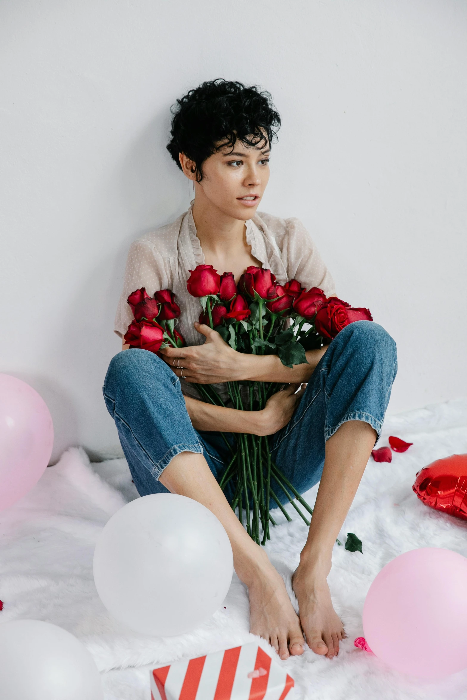 a man sitting on a bed holding a bouquet of roses, curly pixie cut hair, party balloons, mei-ling zhou, promo image