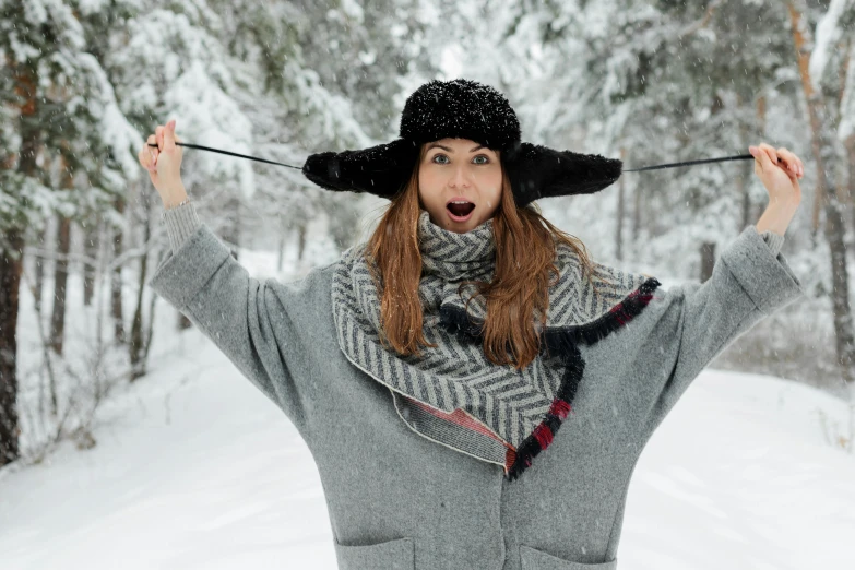 a woman standing in the snow wearing a hat and scarf, pexels contest winner, very silly, grey, thumbnail, black pointed hat