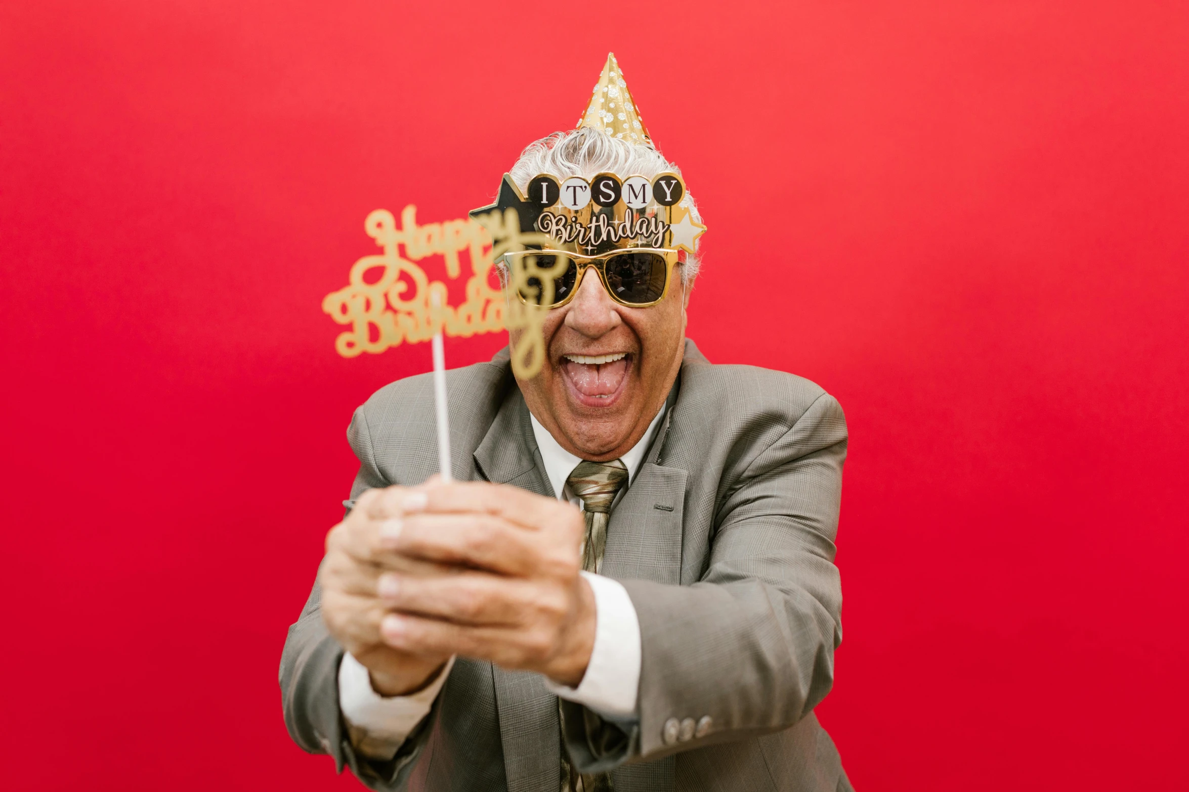 a man in a suit and sunglasses holding a cake topper, pexels, 70 years old, having a good time, man with a crown, photo booth