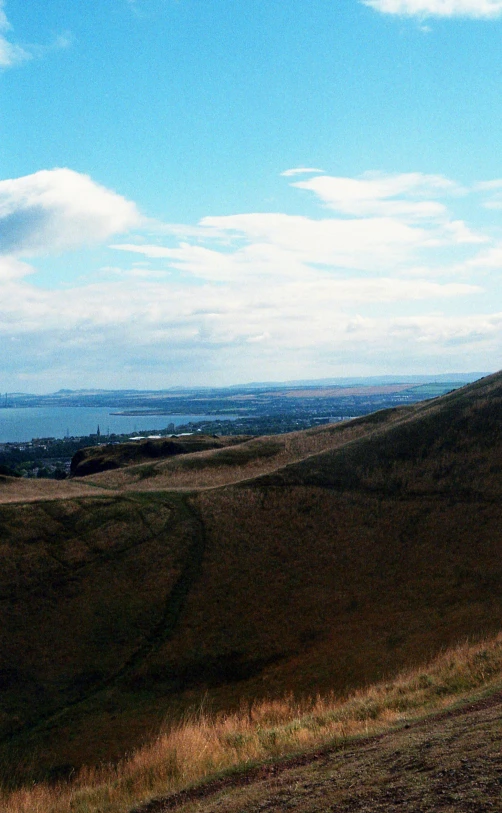 a person riding a bike on top of a hill, paisley, panorama distant view, landscape 35mm veduta photo, daytime