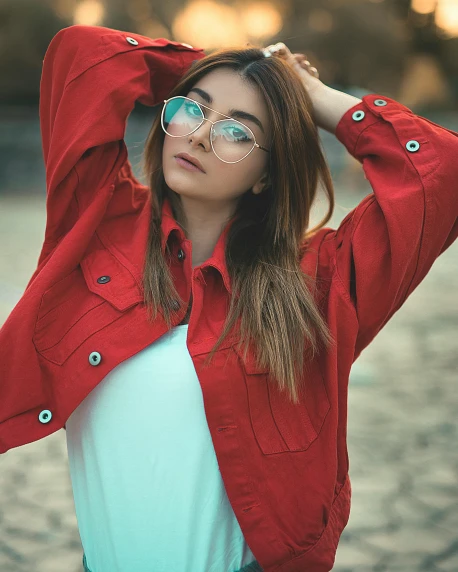 a woman wearing glasses and a red jacket, a colorized photo, inspired by Elsa Bleda, trending on pexels, jean jacket, attractive pose, rainbow clothes, teal silver red
