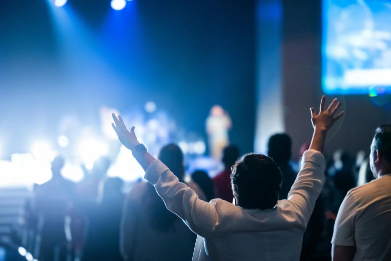 a group of people standing in front of a stage, pexels, happening, scene from church, his arms spread, photo of a man, vibing to music