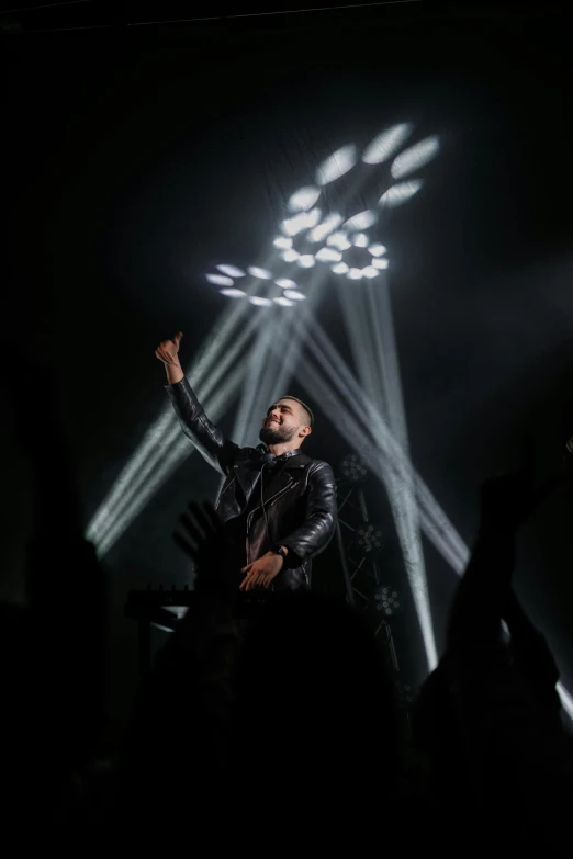 a man standing on top of a stage in front of a crowd, wearing studded leather, lowkey lighting, liam, profile image