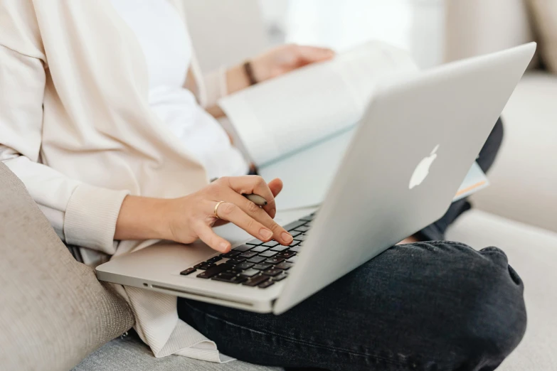 a woman sitting on a couch using a laptop, trending on pexels, worksafe. instagram photo, with apple, sitting with wrists together, student