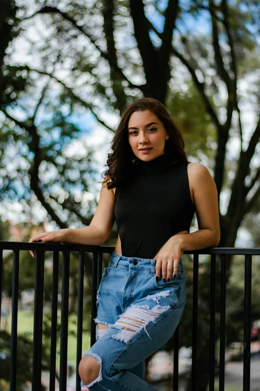 a woman in a black top and jeans leaning on a fence, a portrait, by Robbie Trevino, pexels contest winner, renaissance, portrait sophie mudd, 15081959 21121991 01012000 4k, wearing turtleneck, wearing a tank top and shorts