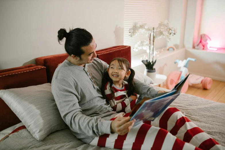 a woman reading a book to a child on a bed, a cartoon, pexels contest winner, red and white stripes, asian man, daddy, wearing pajamas