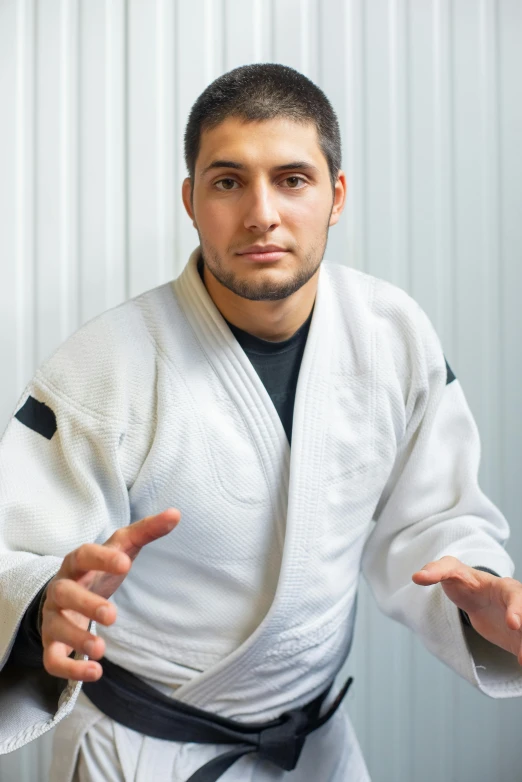 a man in a karate kimono posing for a picture, looking confused, jaime jasso, hispanic, meditating
