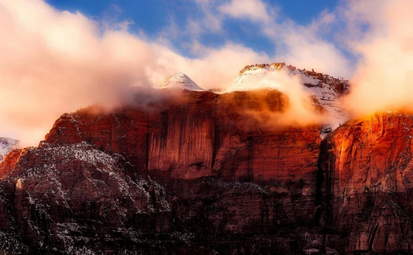 the mountains are covered in snow and clouds, by Lee Loughridge, unsplash contest winner, red sandstone natural sculptures, cliff side at dusk, bright rim light, intense smoldering