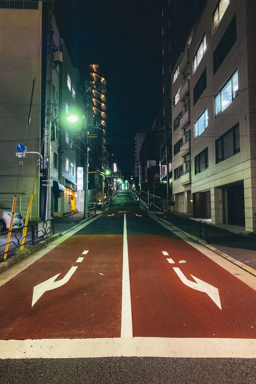 a man riding a bike down a street next to tall buildings, an album cover, unsplash contest winner, street art, quiet tokyo alley at night, traffic signs, damaged streets, empty road in the middle