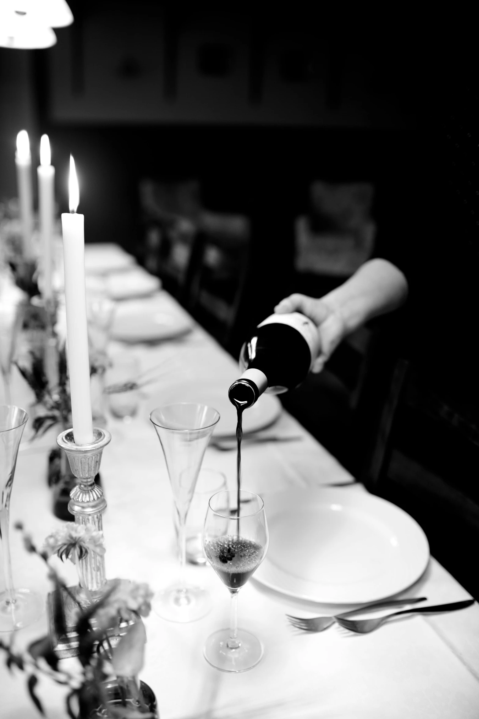 a person pouring wine into a glass at a dinner table, a black and white photo, hasselblad photography, 15081959 21121991 01012000 4k, candlelit, server