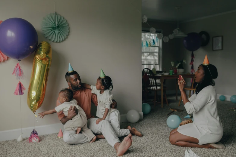 a couple of people that are sitting on the floor, by Carey Morris, pexels contest winner, birthday party, fatherly, varying ethnicities, background image