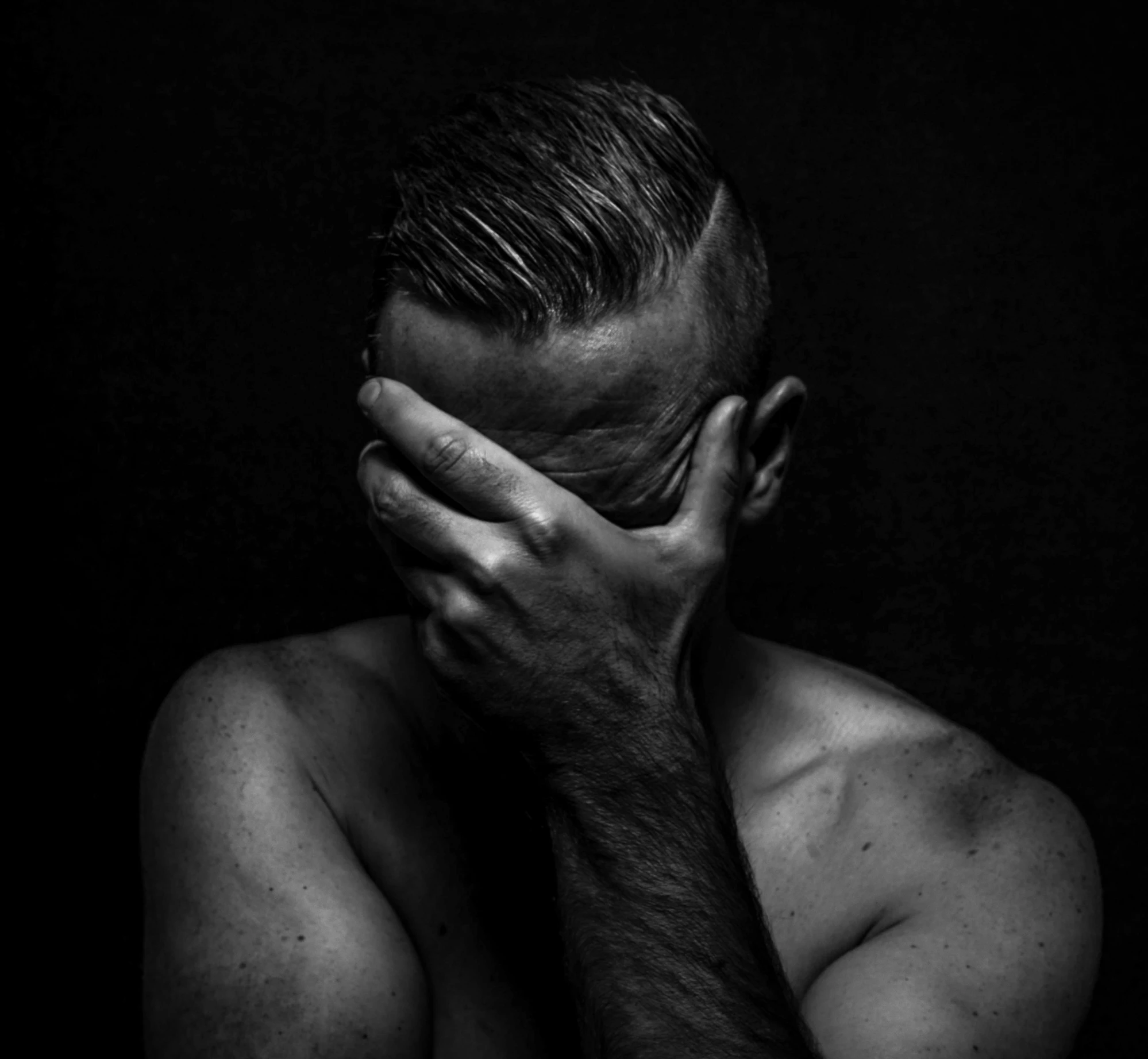 a man covering his face with his hands, a black and white photo, antipodeans, depressed dramatic bicep pose, a portrait of @hypnos_onc, injured, josh black