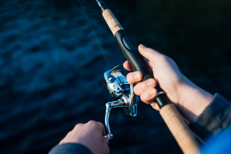 a person holding a fishing rod next to a body of water, a picture, up close, levers, lachlan bailey, high resolution