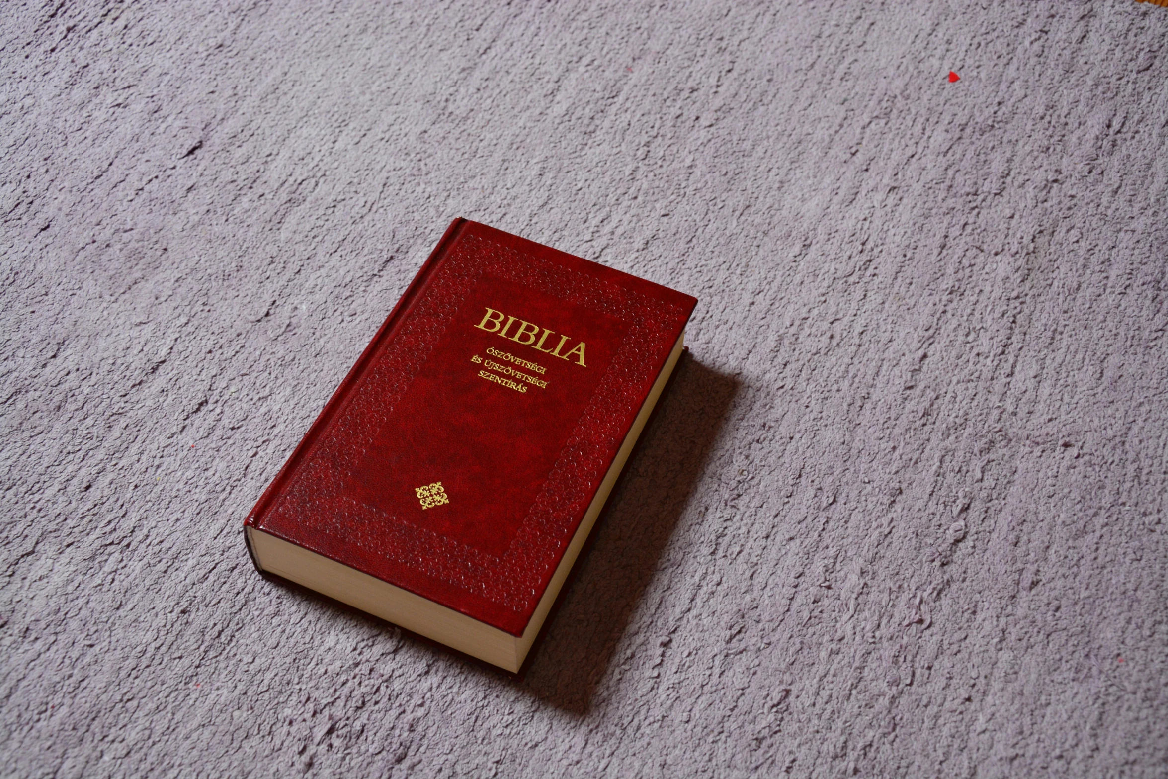 a red bible sitting on top of a white carpet