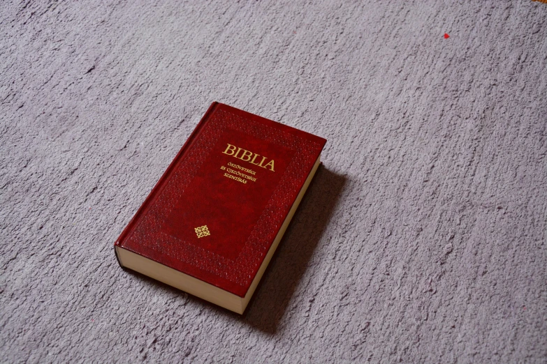 a red bible sitting on top of a white carpet