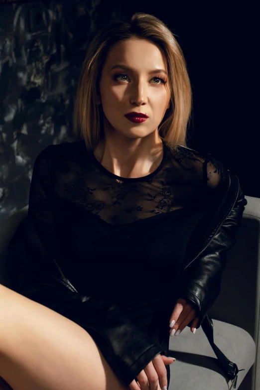 a woman in a black dress sitting on a chair, a portrait, inspired by Ilka Gedő, pexels contest winner, leather top, zoe kazan, revealing clothes, dark lipstick